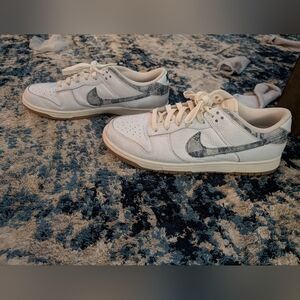 This is a Nike Dunk Low 'New AmericWhite and Gray Sneakers with Patterned Swoosh